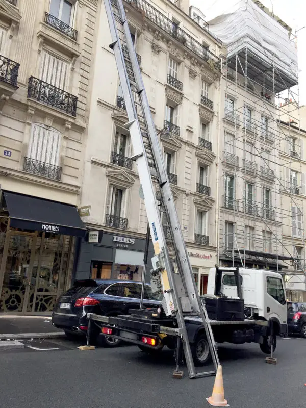 Opérateur de monte-meuble guidant un objet depuis la fenêtre d'un appartement